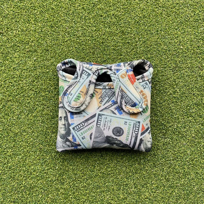 Golf ball marker with dollar bill design on a green surface