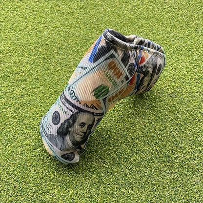 Golf club head cover made from a dollar bill on a green grass background