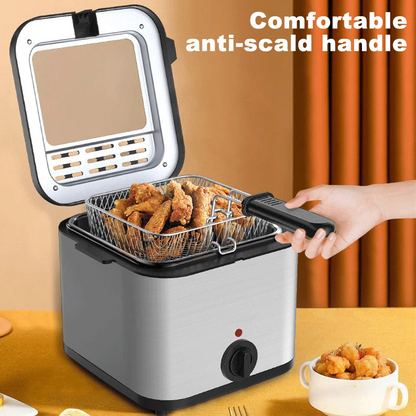 Small deep fryer with a handle holding fried food, placed on a table.