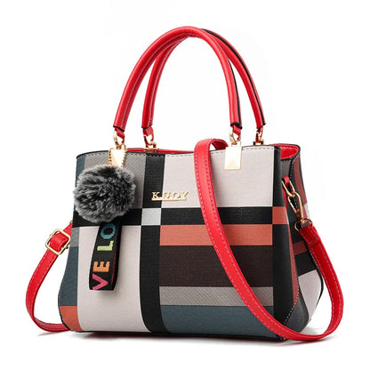 Multicolored checkered handbag with red handles and strap on a white background