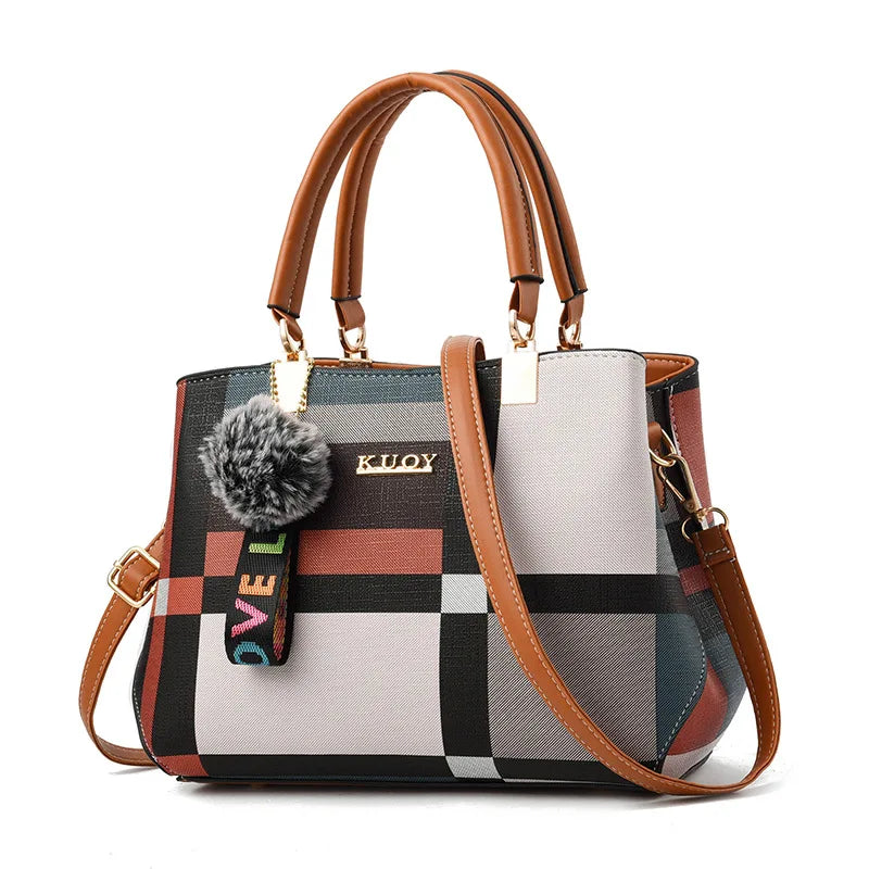 Multicolored checkered handbag with brown handles and strap on a white background
