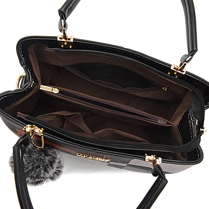 Black handbag with gold accents and a gray pom-pom on a white background