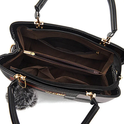 Black handbag with gold accents and a gray pom-pom on a white background