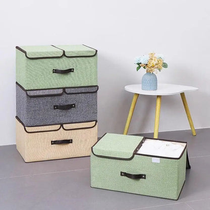 Set of three storage boxes in green, gray, and beige with a small table and vase in the background.