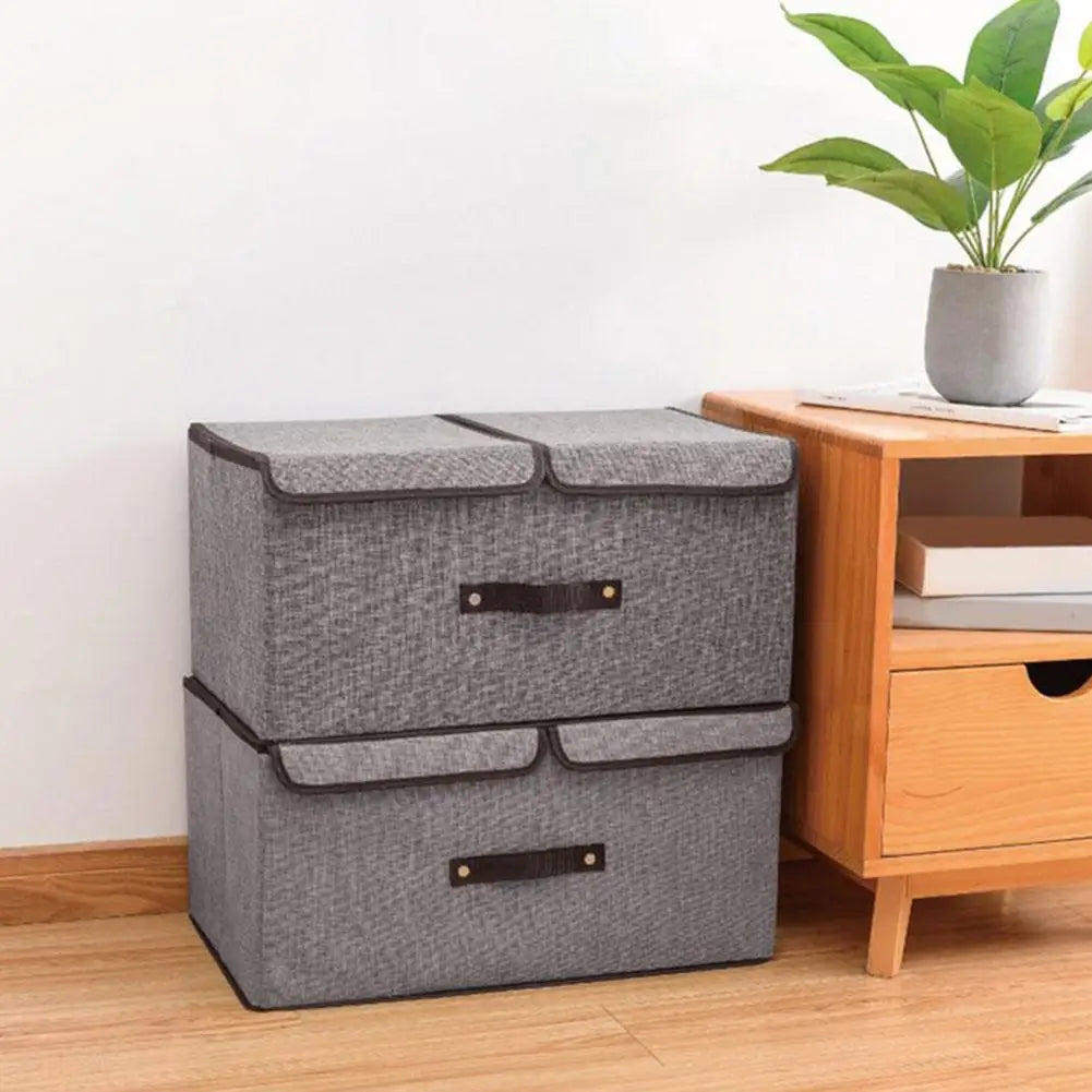 Gray storage ottoman next to a wooden side table with a plant on a light wood floor.