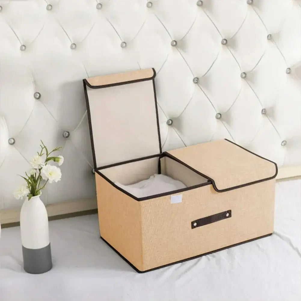 Beige storage box with a lid on a bed against a tufted headboard.