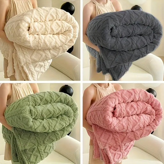 Four different colored textured blankets held by a person on a white couch.
