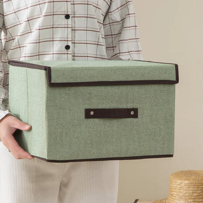 Person holding a green storage box with a brown handle against a neutral background
