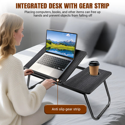 Person using a portable desk with a laptop and coffee cup on a bed.