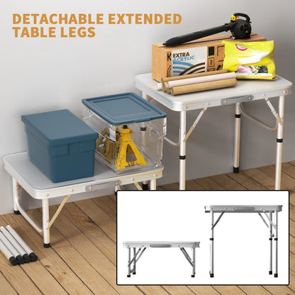 Folding table with detachable extended legs on a wooden floor, with storage containers and tools on top.