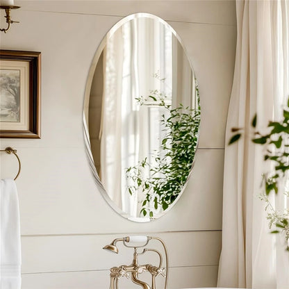 Bathroom with oval mirror reflecting greenery, framed artwork, and towel rack.