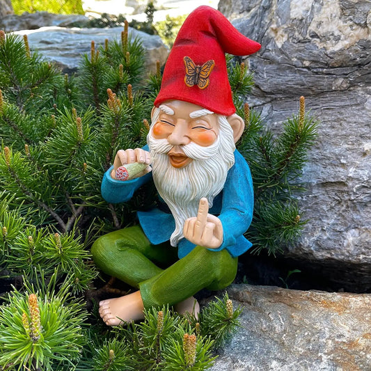 Gnome figurine with a red hat and blue coat sitting among greenery.