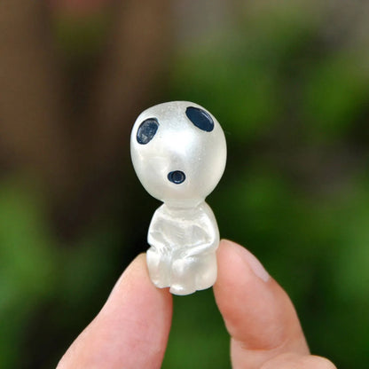 Small alien figurine held in a hand with a blurred green background