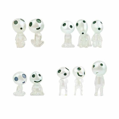 Set of small white figures with black eyes and green accents on a white background