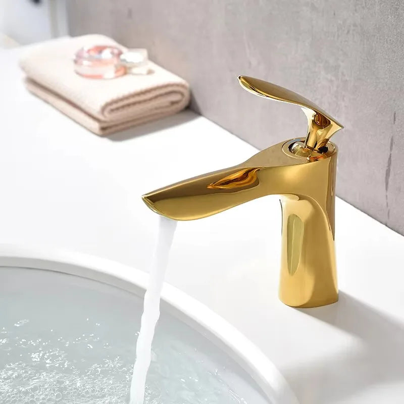 Gold faucet on a sink with water flowing, bathroom setting