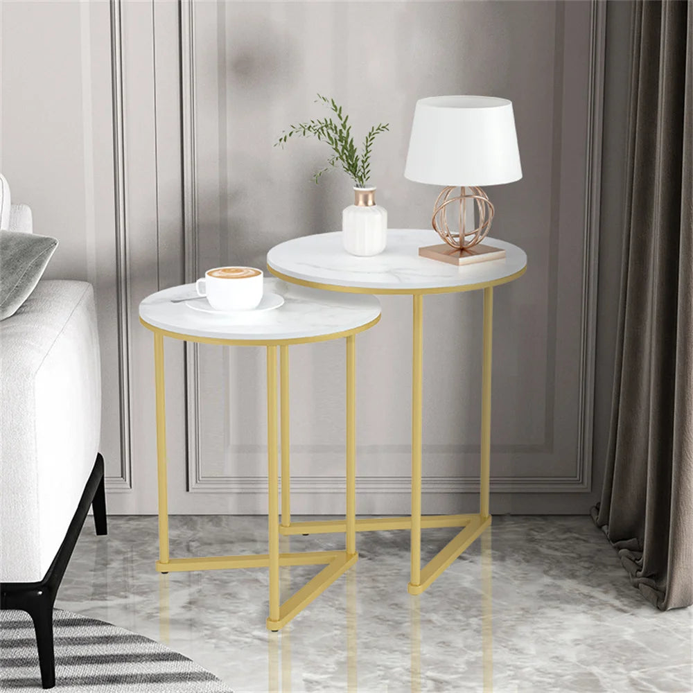 Two round side tables with marble tops and gold frames in a living room setting.