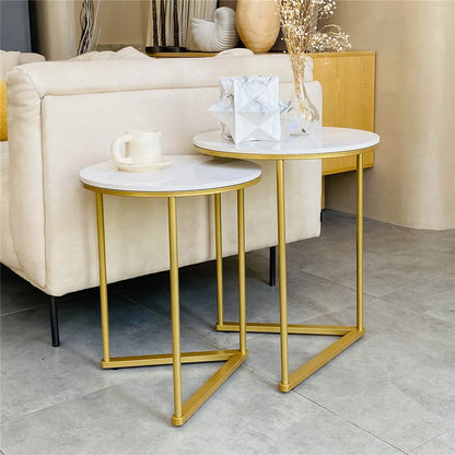 Two gold-framed side tables with marble tops in a living room setting.