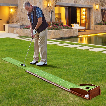 Man playing golf on a putting green mat in a backyard setting.