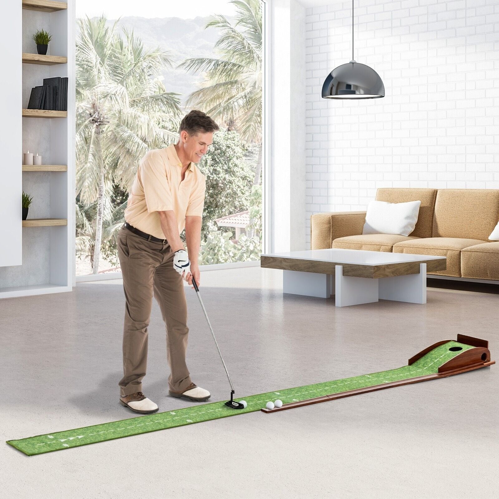 Man playing mini golf indoors on a green mat with a living room in the background