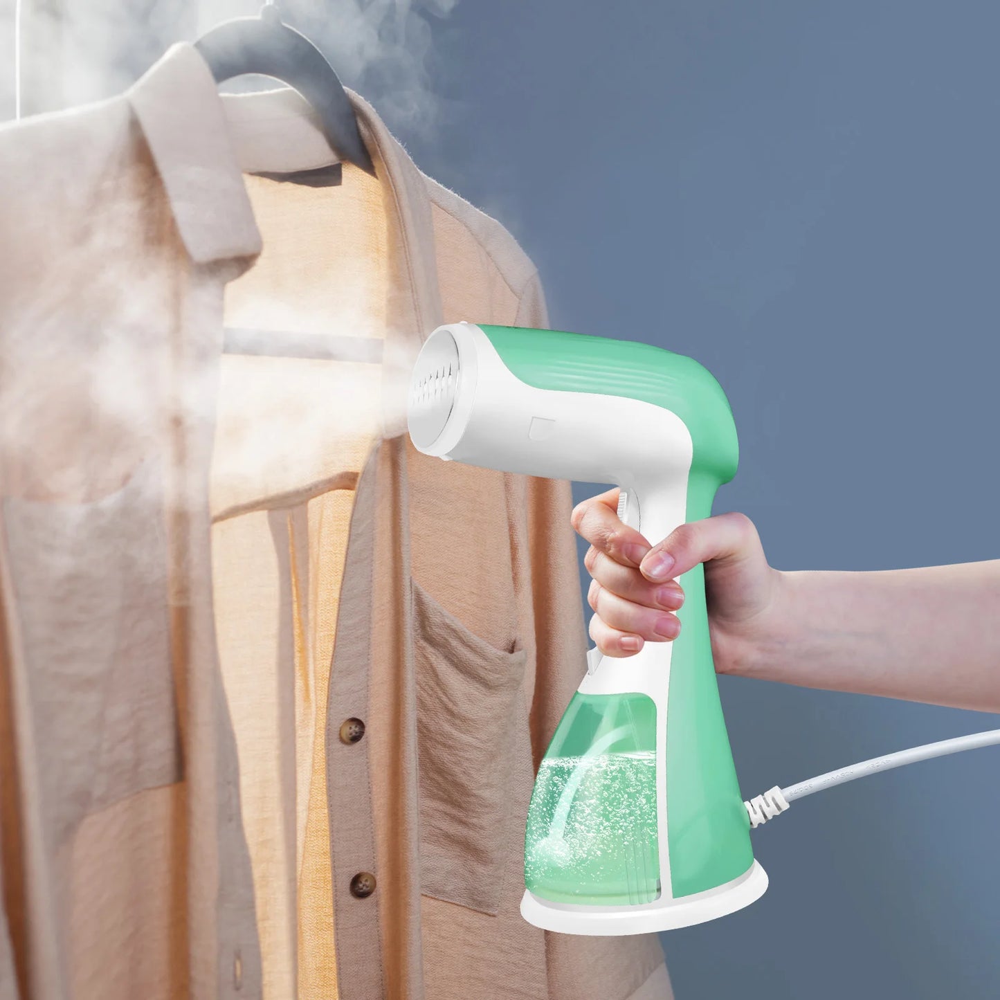 Hand holding a green and white handheld steamer over a shirt against a blue background