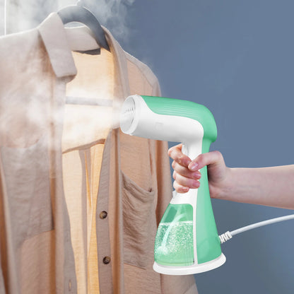 Hand holding a green and white handheld steamer over a shirt against a blue background