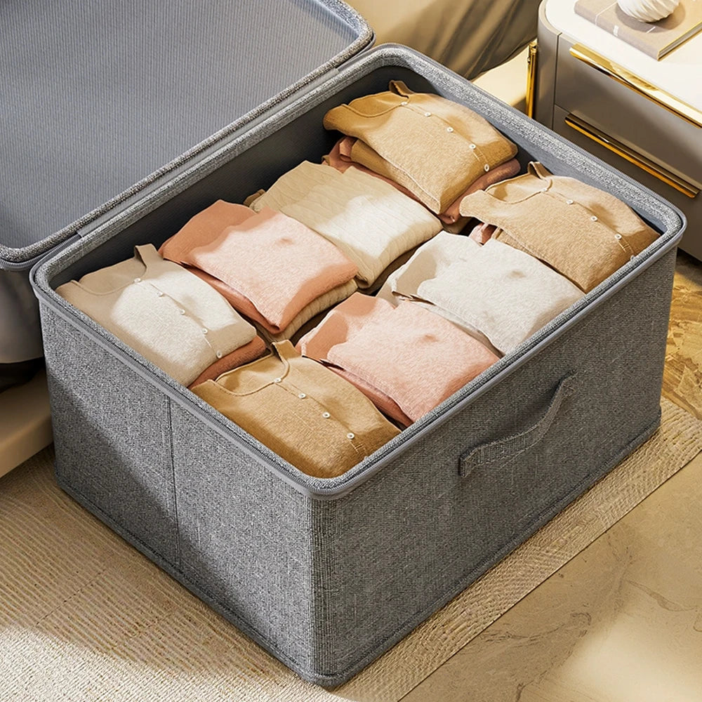Gray storage box filled with folded clothes on a wooden floor.