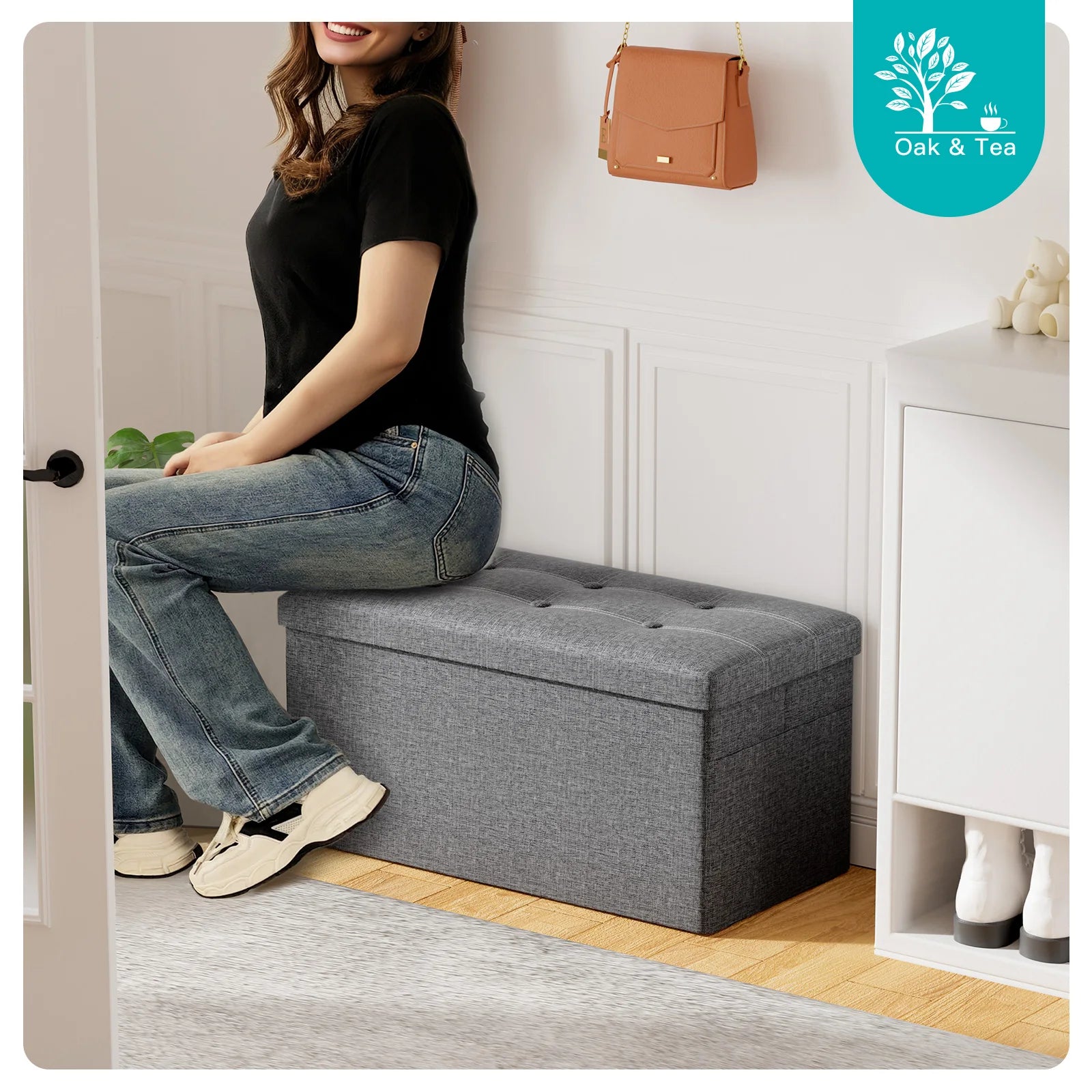 Person sitting on a gray storage bench in a room with a visible brand logo.