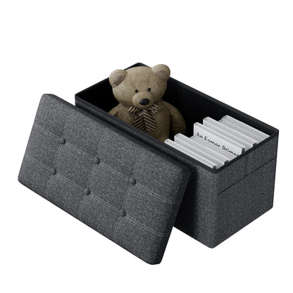 Gray storage ottoman with a teddy bear and books inside on a white background