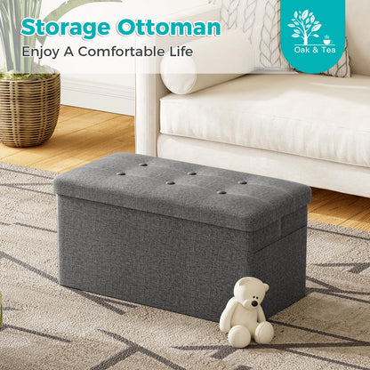 Gray storage ottoman in a living room setting with a teddy bear and 'Oak & Tea' branding.