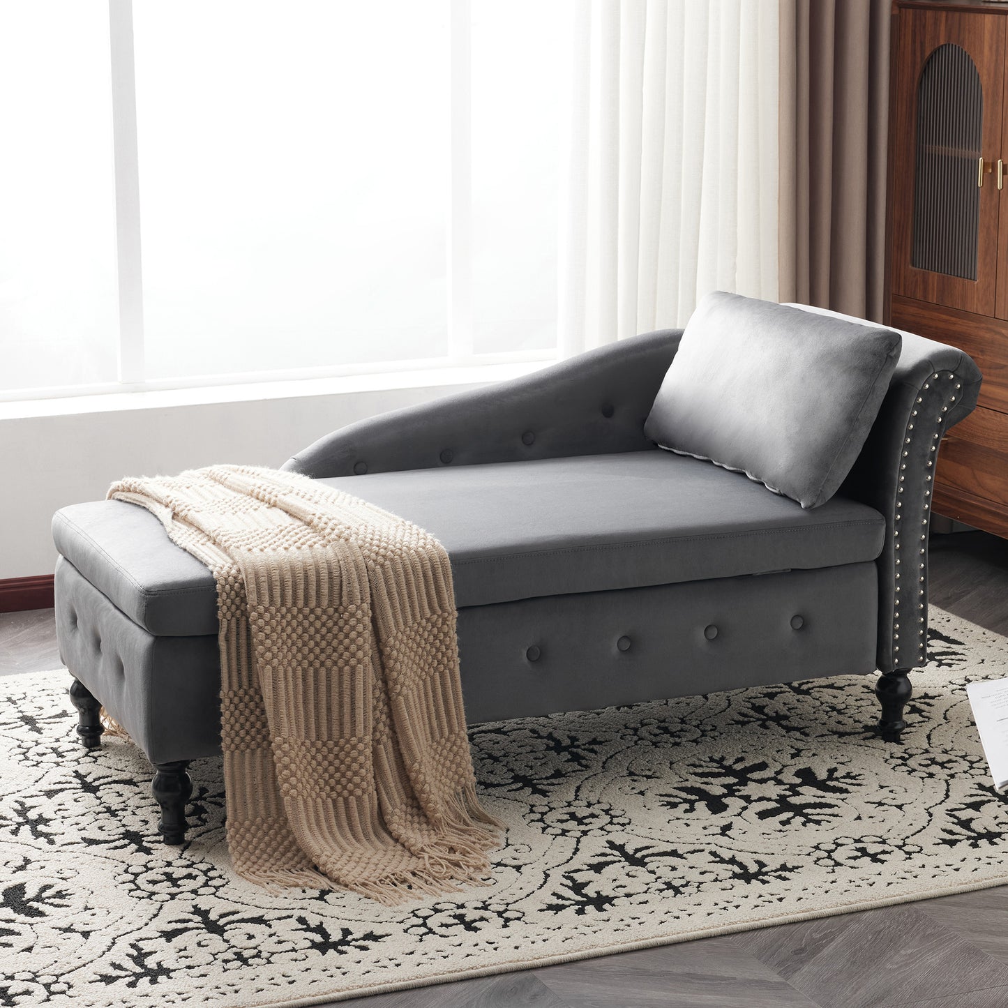 Gray chaise lounge with a beige blanket on a patterned rug in a room with wooden furniture.