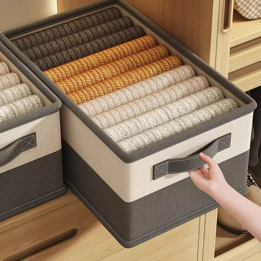 Storage bins with rolled-up clothes on a wooden surface