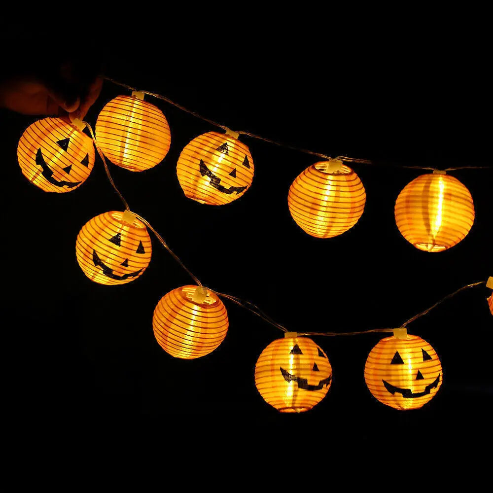 String of Halloween-themed paper lanterns with jack-o'-lantern faces on a black background.