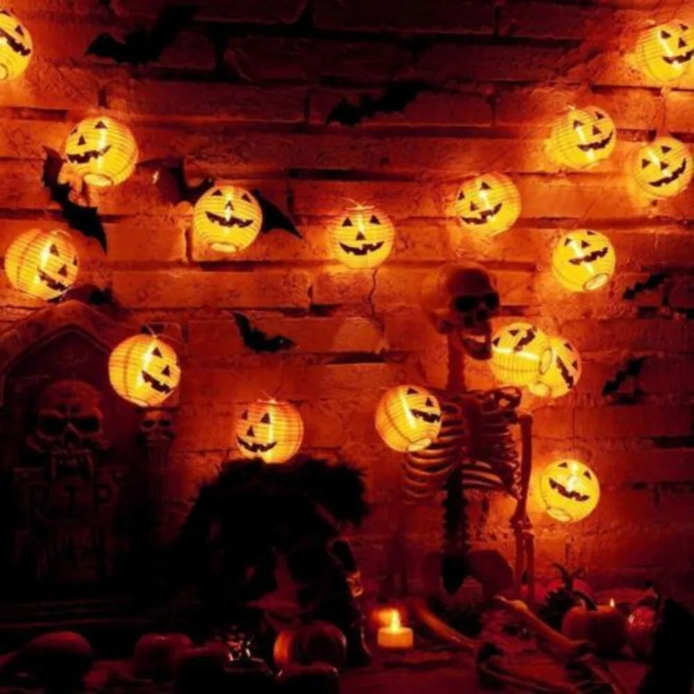 Halloween-themed string lights with jack-o'-lantern design on a brick wall.