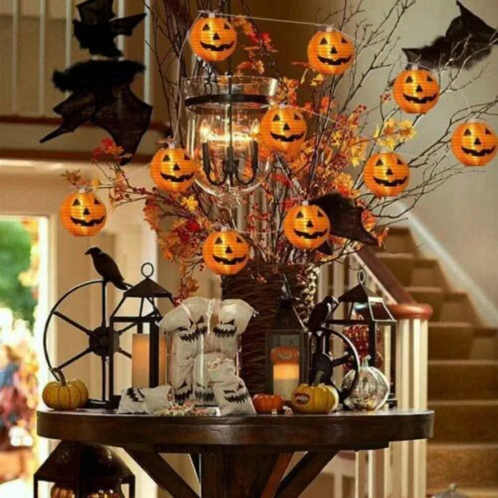 Halloween-themed table decoration with pumpkins, bats, and candles.