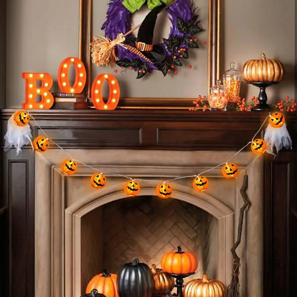 Halloween-themed fireplace mantel with decorative pumpkins, lights, and wreath.