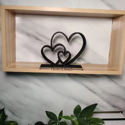 Decorative metal heart sculpture in a wooden frame with plant in the foreground