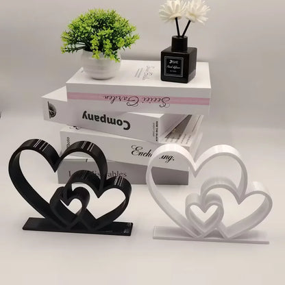 Black and white heart-shaped decorative items on a white surface with books and a plant in the background.