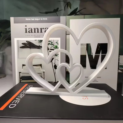 White heart-shaped decorative item on a surface with books in the background