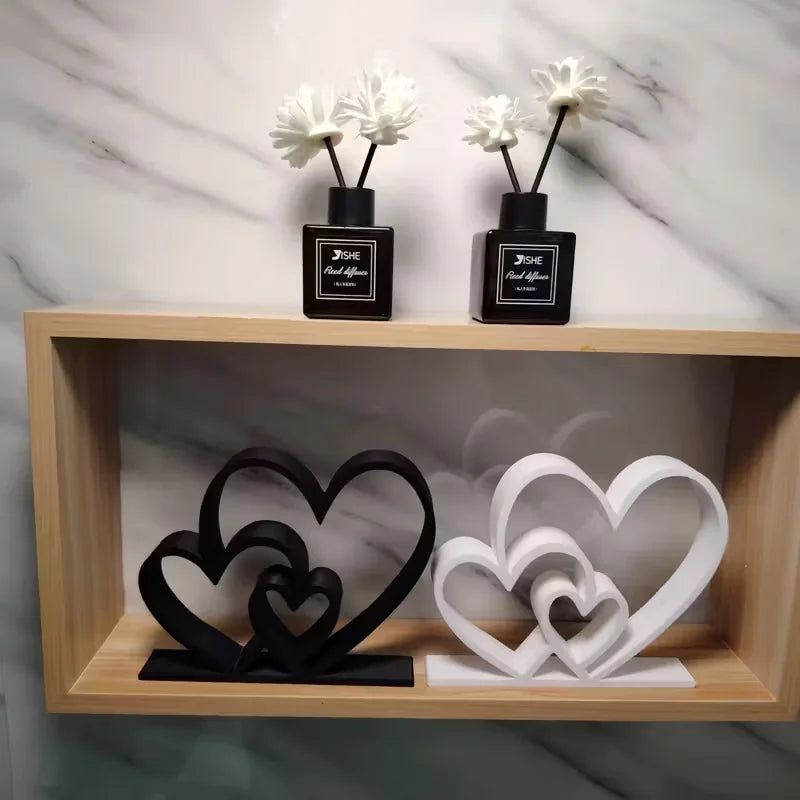 Decorative heart-shaped sculptures and black diffusers on a wooden shelf against a marble wall.