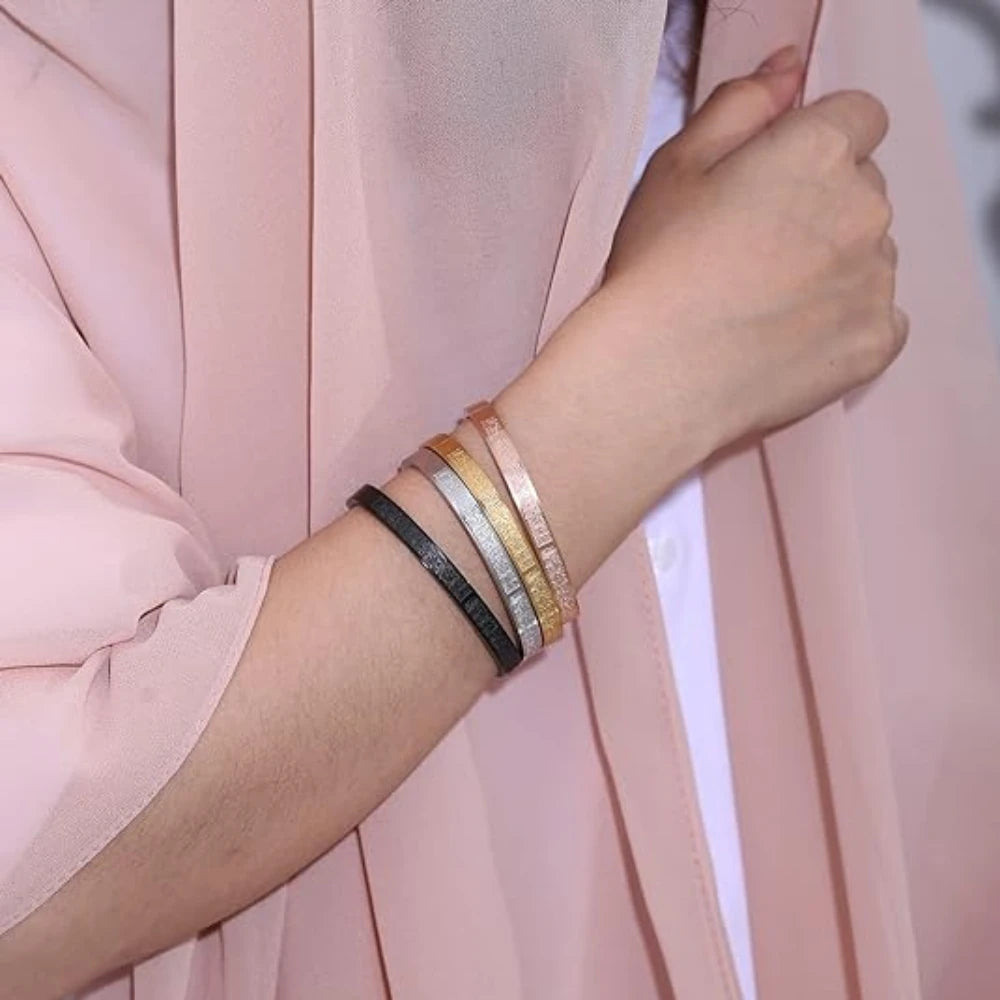 Close-up of a wrist wearing multiple bracelets against a pink background