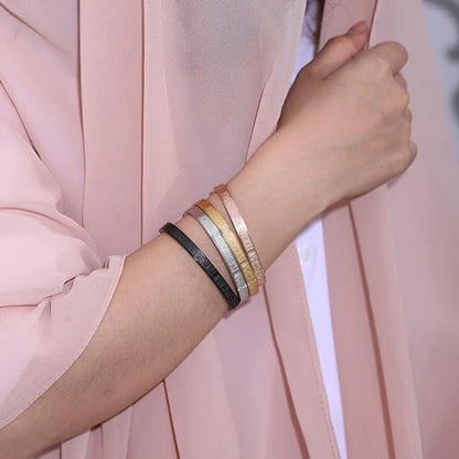 Close-up of a wrist wearing multiple bracelets against a pink background