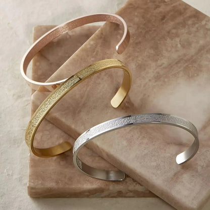 Two gold and one silver bracelet on a marble surface