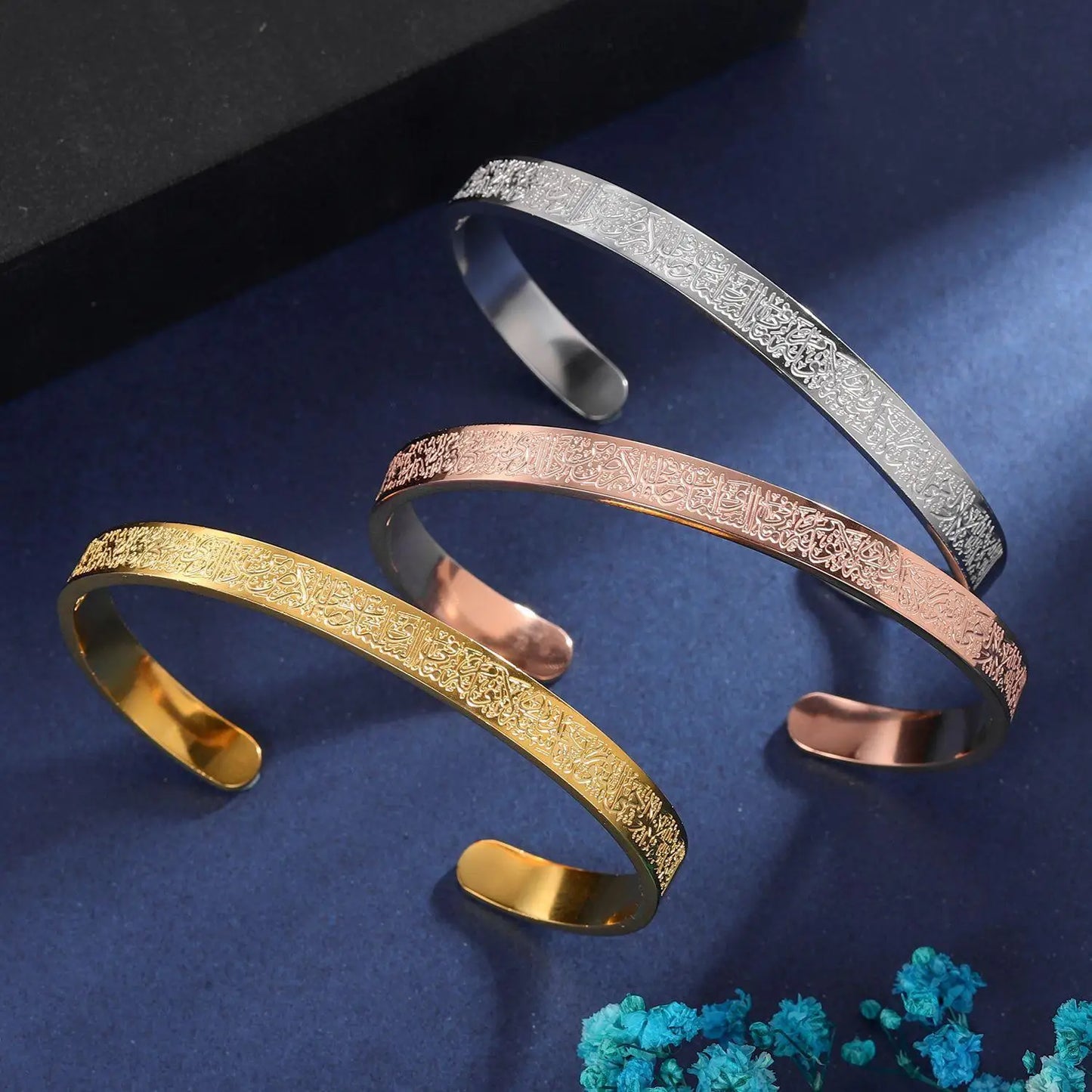 Three gold, silver, and rose gold bangles on a dark blue background