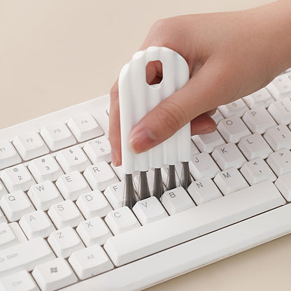 Hand using a white keyboard cleaning tool on a white keyboard.
