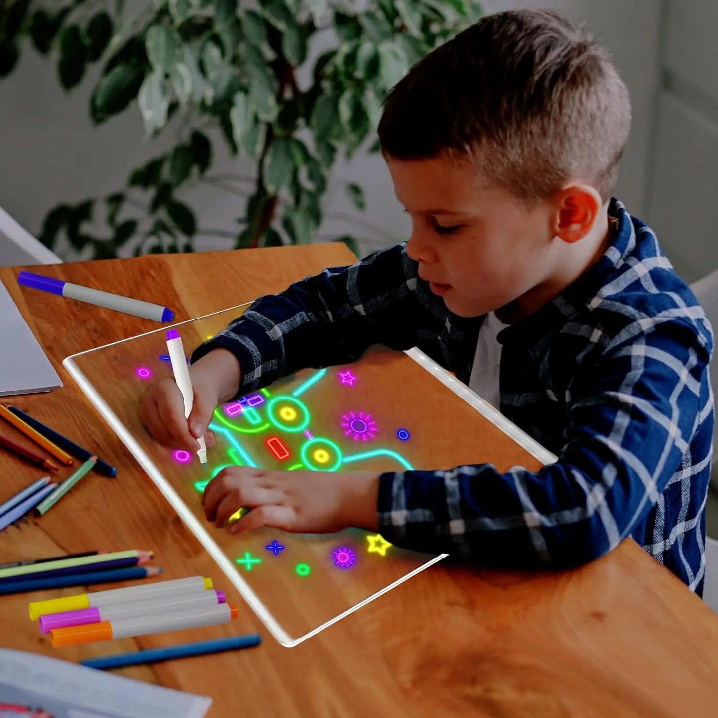 Child drawing on a transparent board with colorful markers at a wooden table.