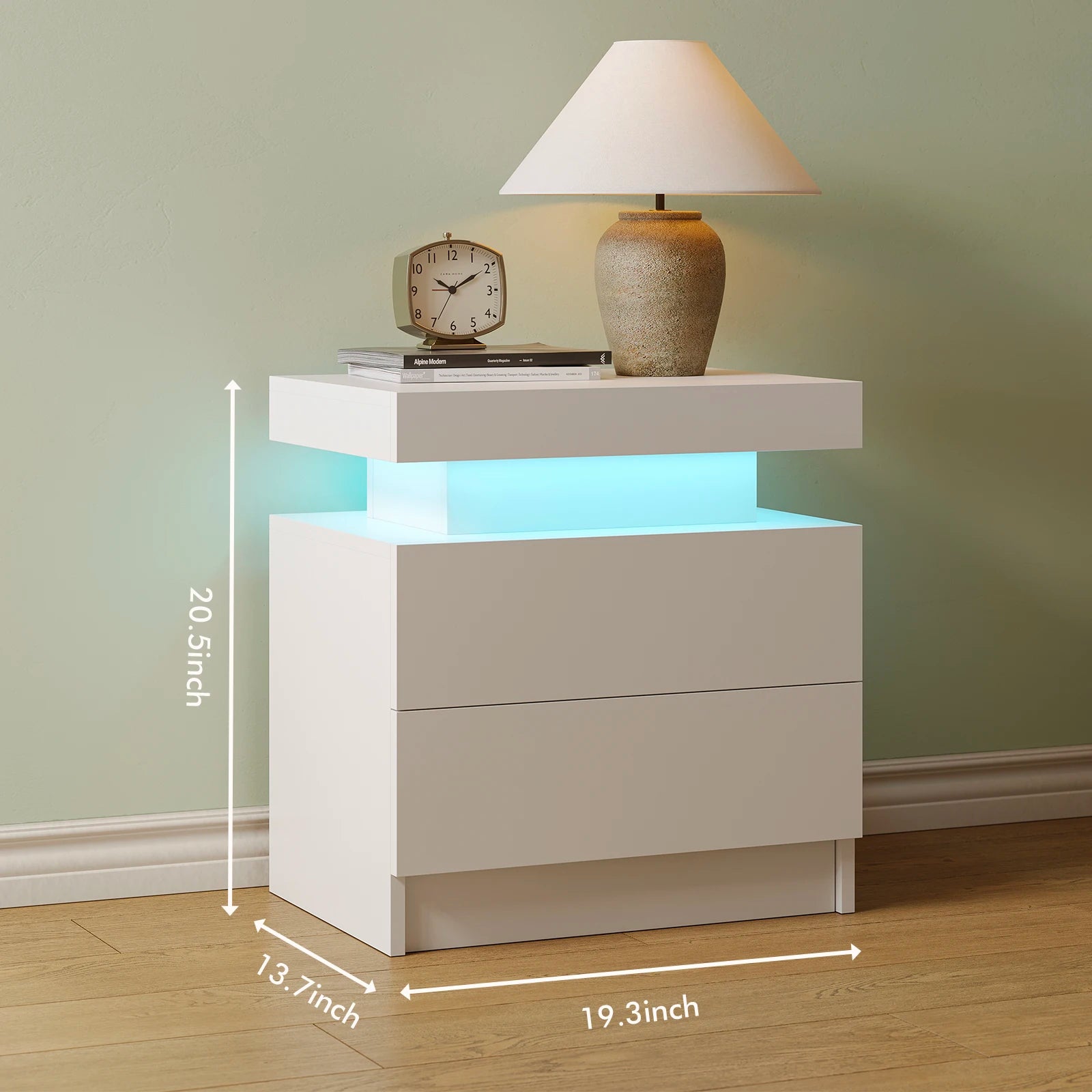 White nightstand with LED lighting, lamp, and clock on a wooden floor with a green wall.