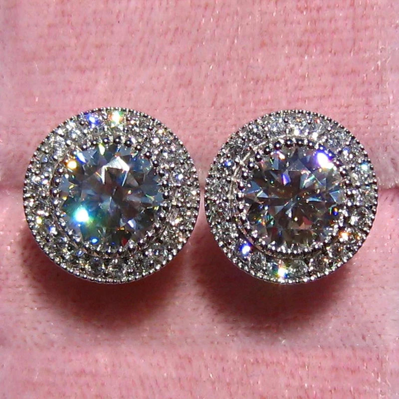 Pair of round diamond earrings on a pink background
