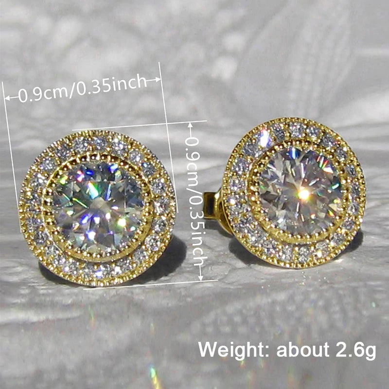 Gold and diamond earrings with measurements and weight information on a reflective surface.
