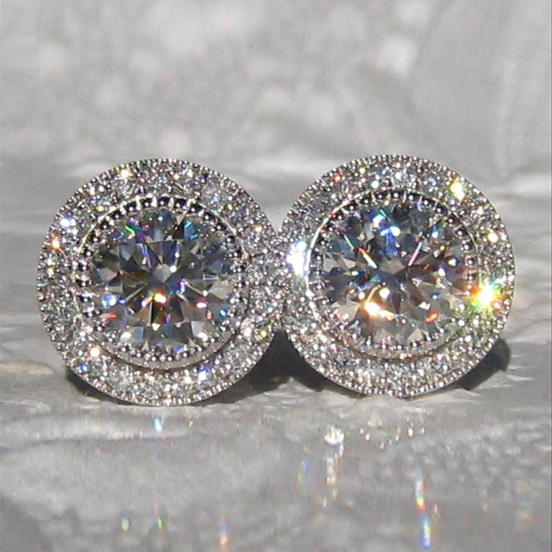 Pair of diamond stud earrings on a reflective surface