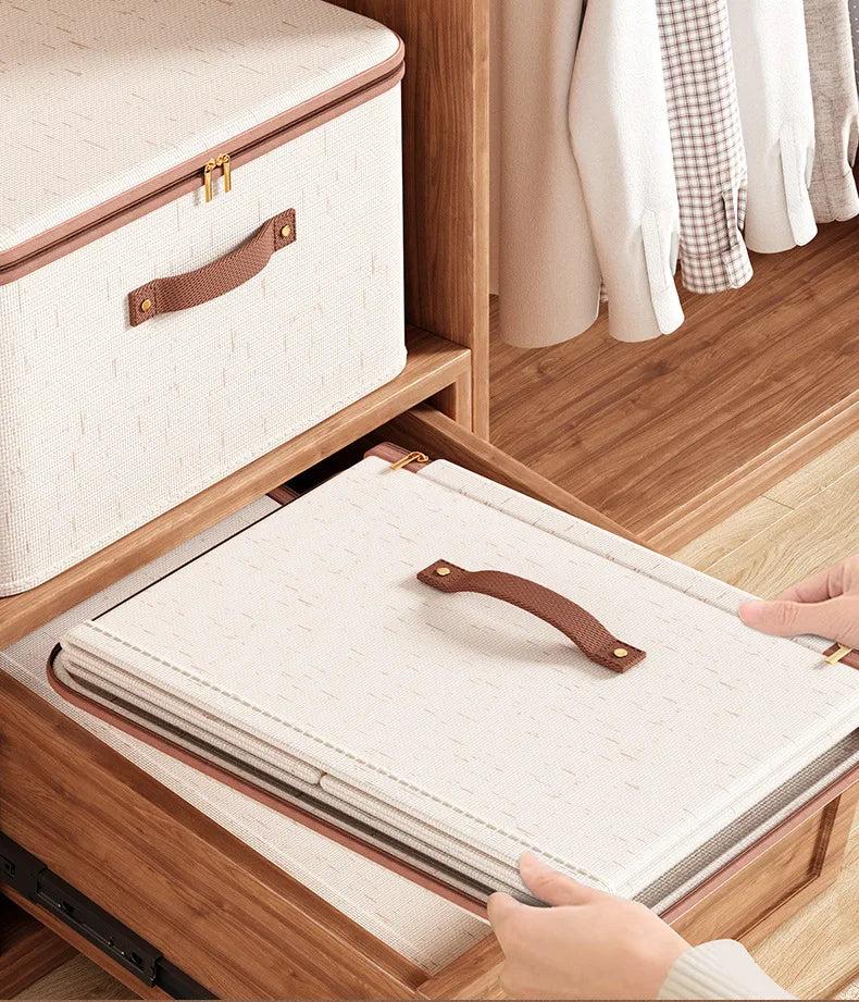 Person opening a wooden drawer with a fabric storage box inside, surrounded by clothes on hangers.